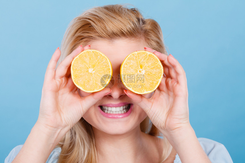 女少手里握着两半黄柠檬柑橘水果眼睛遮着蓝色健康饮食营养幸福快乐概念女孩用柠檬柑橘水果遮住眼睛图片