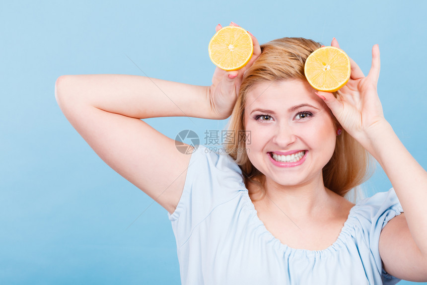 怀着两半黄柠檬柑橘水果的年轻女孩手握着两半黄柠檬柑橘水果蓝着健康饮食营养图片