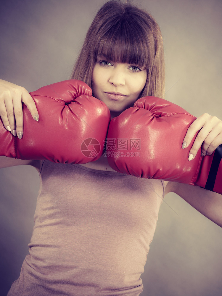 手持红色拳击套打斗的运动女工作室拍摄的灰色背景图片