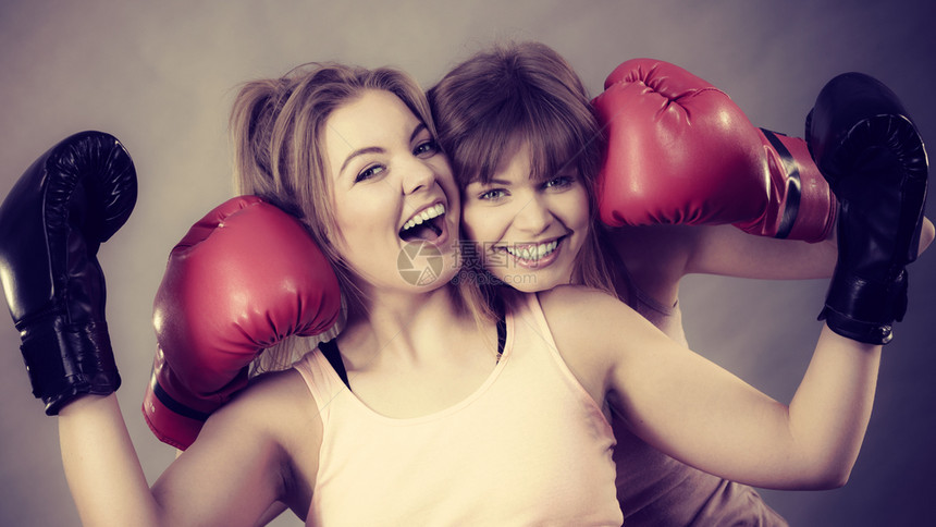 友谊人际关系概念两个快乐的女朋友带着拳击手套快乐地笑着穿拳击手套图片