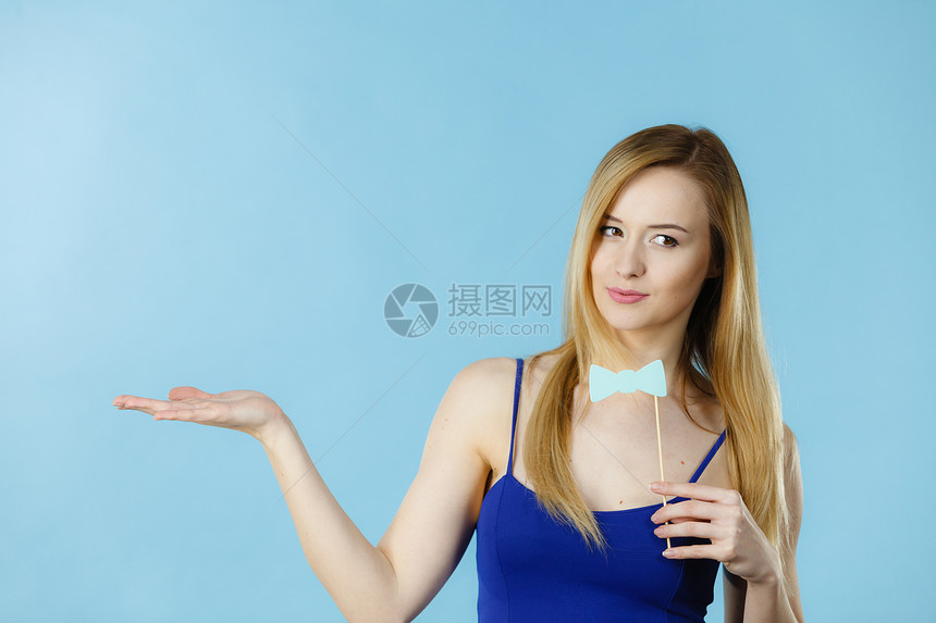 拿着狂欢节附属品的女人在玩蓝色背景的摄影棚拍摄拿着嘉年华附属品的女人图片