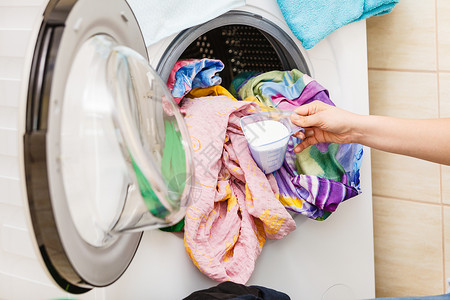 将衣物装进洗机的人用具家务义概念图片
