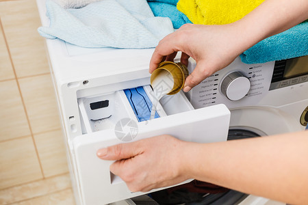 织物柔软剂洗粉涤剂和测量杯子倒进机器中家务衣物洗涤剂概念衣粉涤剂背景