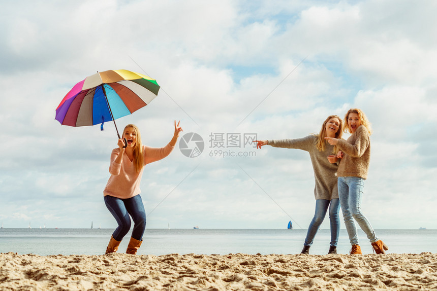 三个充满欢乐的女子在一起玩得很开心一个女人拿着多彩的雨伞女人拿着和朋友玩得开心图片