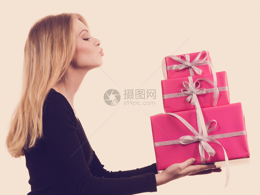 可爱的金发女孩拿着一堆粉红礼物盒送吻在白色上图片