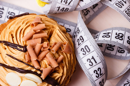 美味和贪食的概念肥成问题蛋糕桌上有测量磁带背景图片