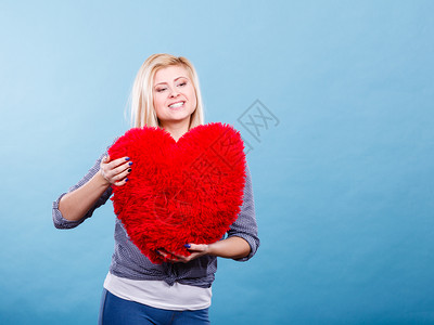 爱浪漫情人节礼物概念快乐的女士带着大红毛发枕头心型快乐的女士抱着红枕头心型背景图片