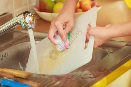 在厨房清洁塑料切割板上洗衣服的近身妇女图片
