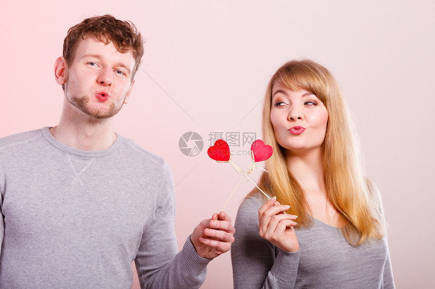 年轻的情侣拿着爱心标签玩耍图片