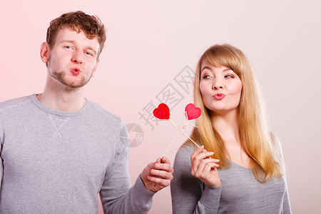 年轻的情侣拿着爱心标签玩耍背景图片