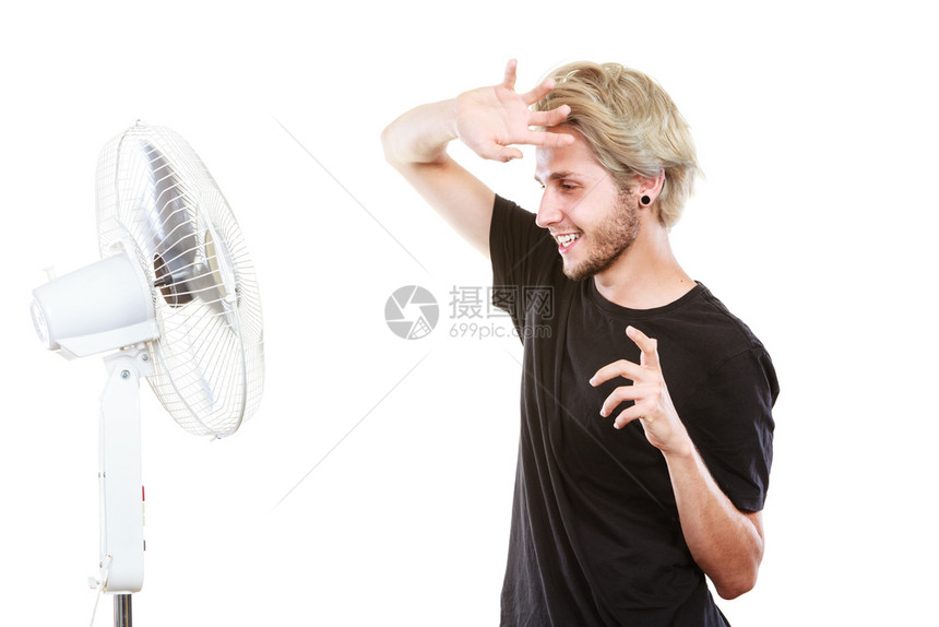 年轻人站在冷却风扇前以艺术方式与风搏斗保持头发工作室被孤立图片