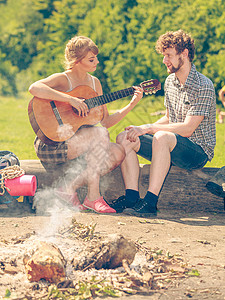 旅游冒险一起享受夏天时光年轻夫妇旅游者在户外露营时玩吉他乐图片