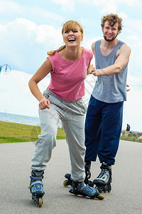 身着运动服的年轻女青将男朋友拉着手在赛道上打滚球妇女鼓励男子打滚球图片