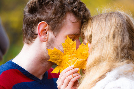 情侣用树叶遮住亲吻的脸颊图片