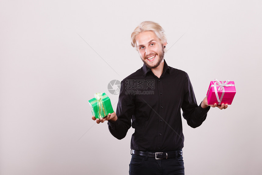 盛的年轻男子拿着粉红和绿色礼品盒手拿着两个礼品盒图片