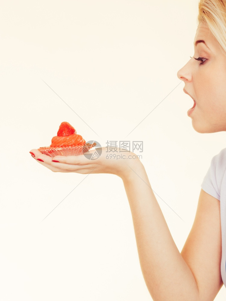糖果垃圾食品糖诱惑的饮食观念拿着香甜可口的纸杯蛋糕的女人正要咬一口拿着香甜可口的纸杯蛋糕的女人图片