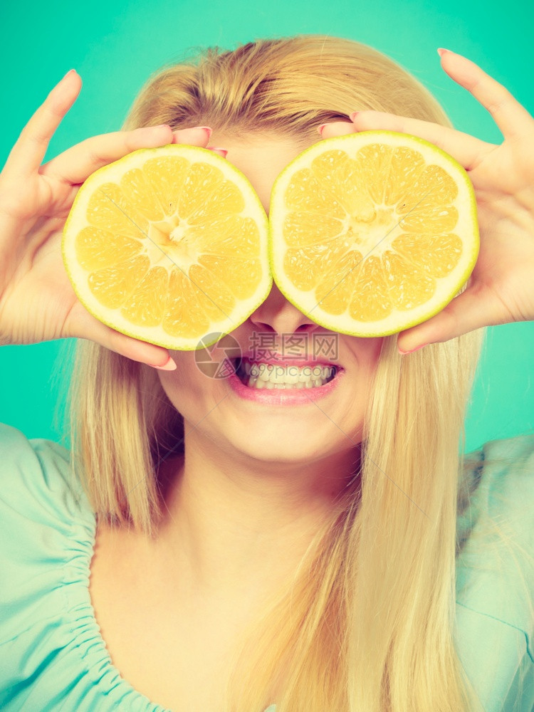 金发女少手拿着两半黄葡萄果柑橘水蒙上眼睛涂蓝色绿健康饮食营养幸福快乐概念女孩用葡萄汁蒙上眼睛图片