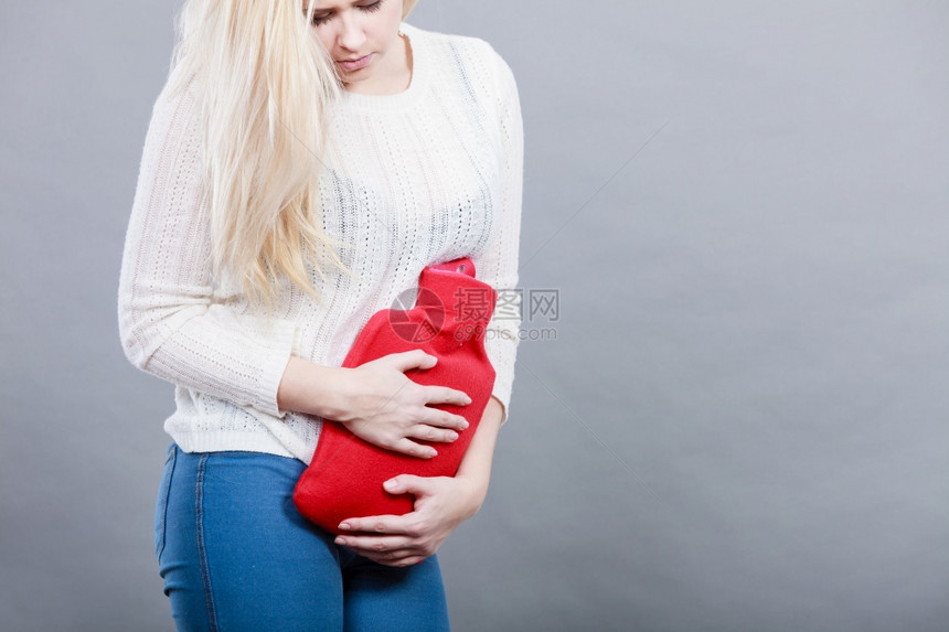 胃痛期和月经抽筋问题概念有腹部抽筋的妇女拿着热水瓶感觉非常不舒服妇女拿着热水瓶感到胃部抽筋图片