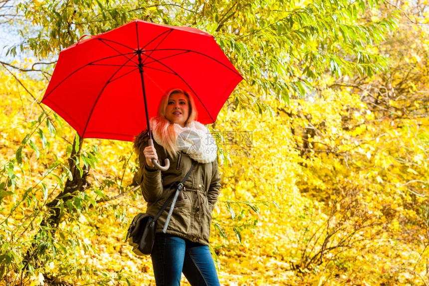 女带着红色雨伞在公园行走秋天气明亮女带着雨伞在公园行走图片