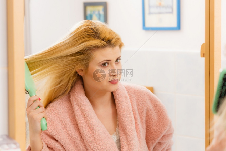 穿着睡衣的女士在梳理她长金发早美常规理发和概念图片