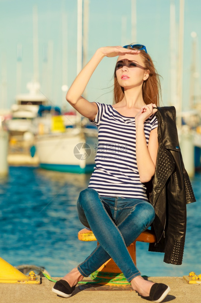 时装金发女孩蓝色心型太阳眼镜在码头对港口的游艇图片