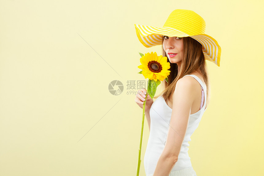 穿着草帽手握向日葵持黄色背景的夏日特勤有吸引力的妇女图片
