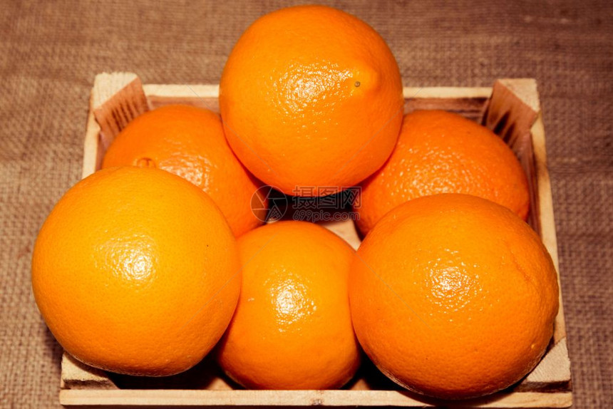 在旧的烧熟木制箱或有麻布背景的盒子中鲜熟橙水果图片