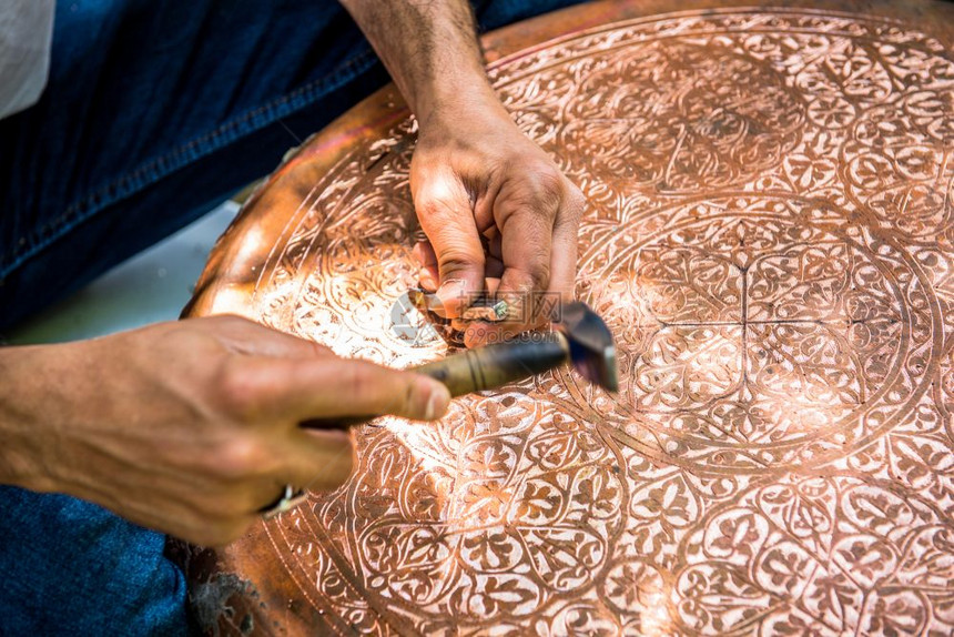 高级工匠铁在金属板上手工压或雕刻装饰图案时用锤子工作图片