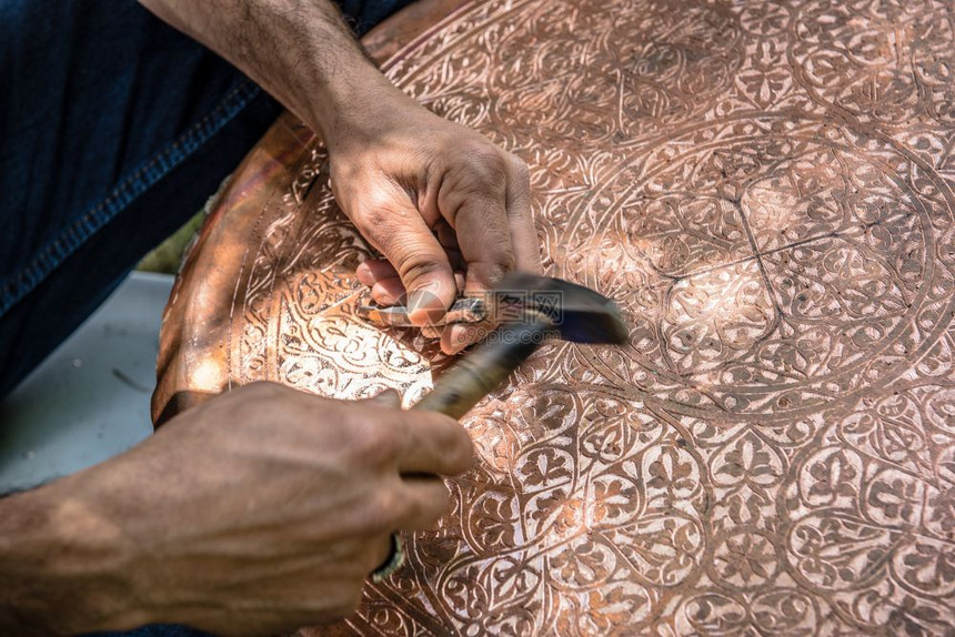 高级工匠铁在金属板上手工压或雕刻装饰图案时用锤子工作图片