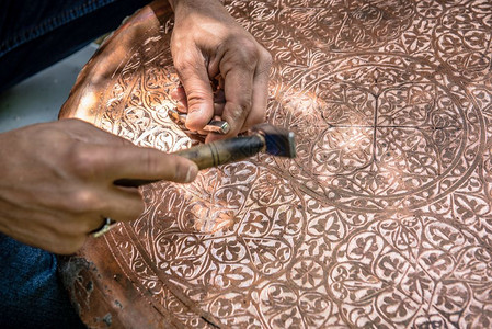 金属压模高级工匠铁在金属板上手工压或雕刻装饰图案时用锤子工作背景