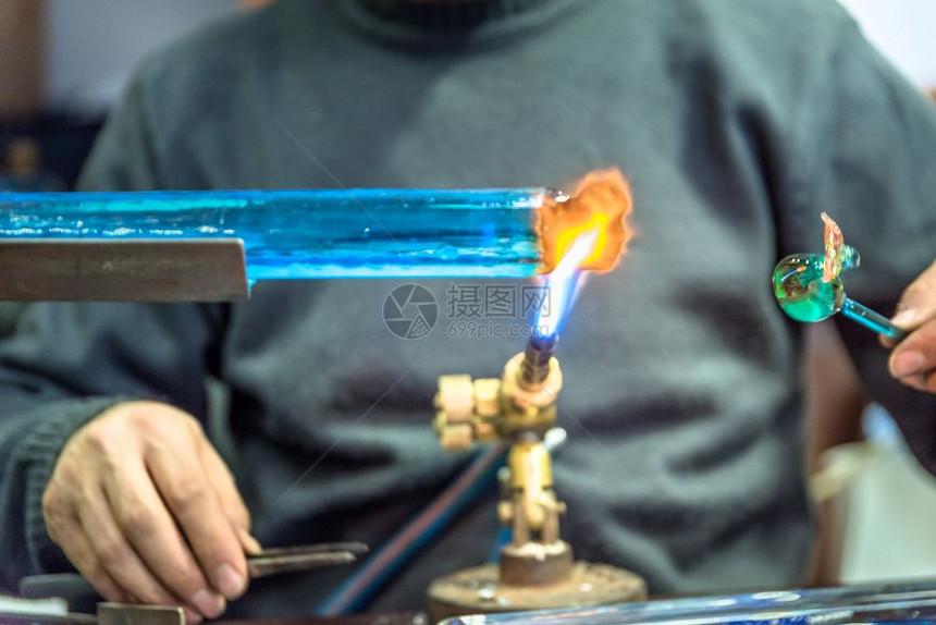 手工艺人用品的在集市上制作玻璃标本Glass制造商用燃烧的火炬制成熔化玻璃将喷灯的火焰贴近新玻璃艺术品手工人在品集市上制作玻璃标图片