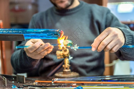 手工艺人用品的在集市上制作玻璃标本Glass制造商用燃烧的火炬制成熔化玻璃将喷灯的火焰贴近新玻璃艺术品手工人在品集市上制作玻璃标背景