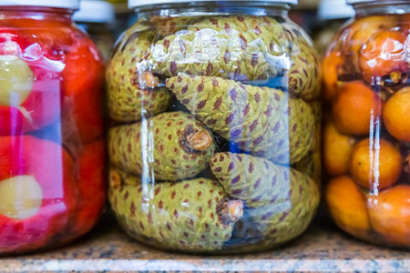 绿色松瓜泡菜在玻璃罐中展示出售绿色松锥瓜在玻璃罐中销售图片