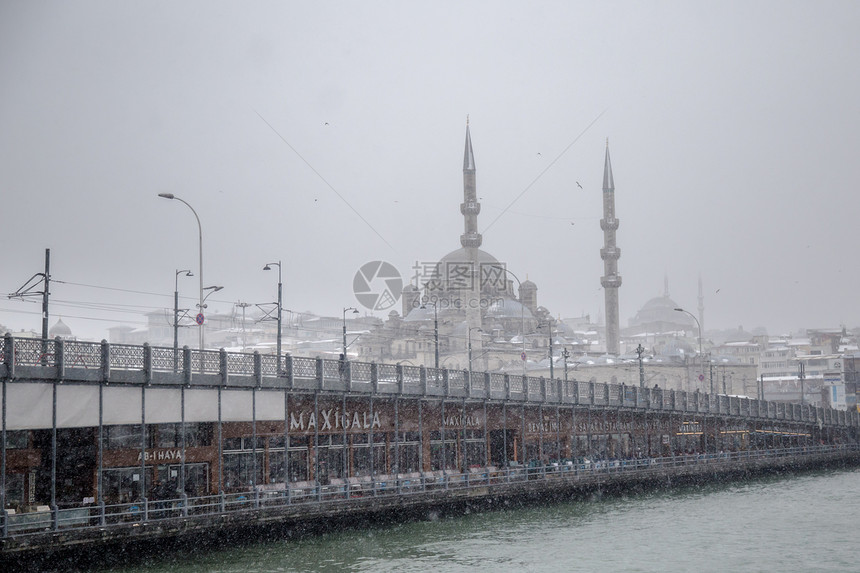 受欢迎的新莫斯格大桥和加拉塔大桥的冬季海景在冬天的雪天海鸥飞过博斯普鲁斯海峡流行的新莫斯格和加拉塔大桥的冬季海景图片