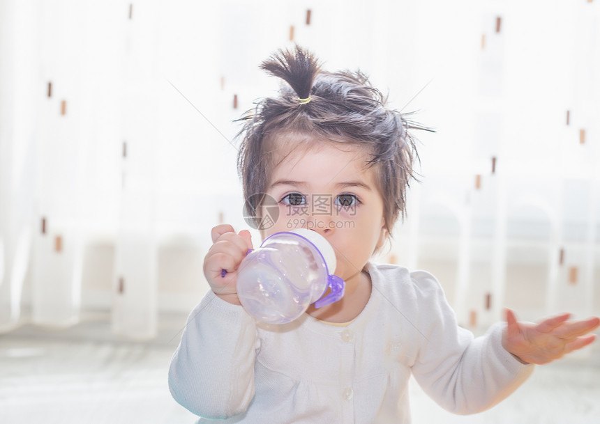 可爱小女婴的肖像她抱着可爱的小女婴用瓶子和饮水喝着可爱小女婴的肖像图片