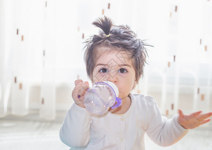 可爱小女婴的肖像她抱着可爱的小女婴用瓶子和饮水喝着可爱小女婴的肖像图片