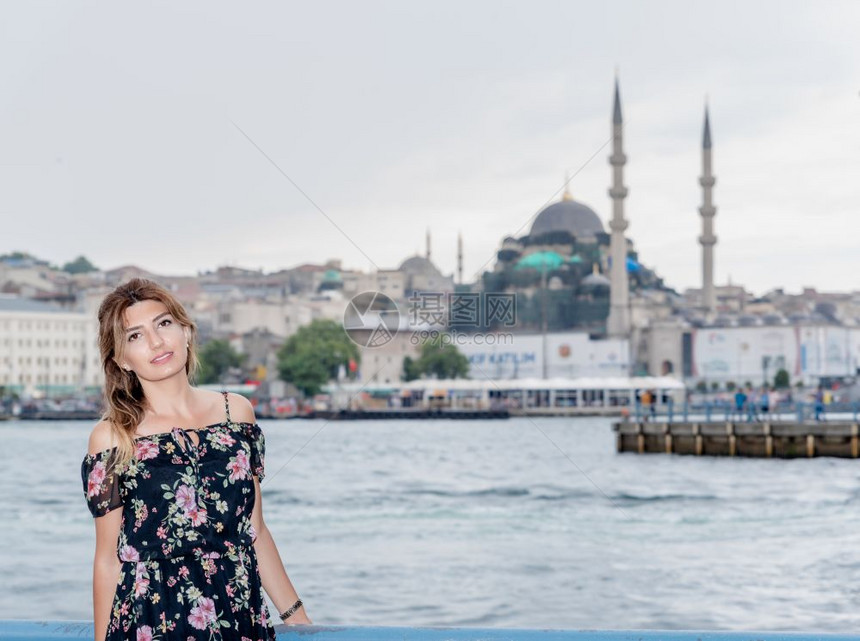 在土耳其伊斯坦布尔的加拉塔桥新清真寺和埃米诺努镇的土耳其伊斯坦堡美丽的女肖像美丽女乘渡轮往返于亚洲和欧之间图片