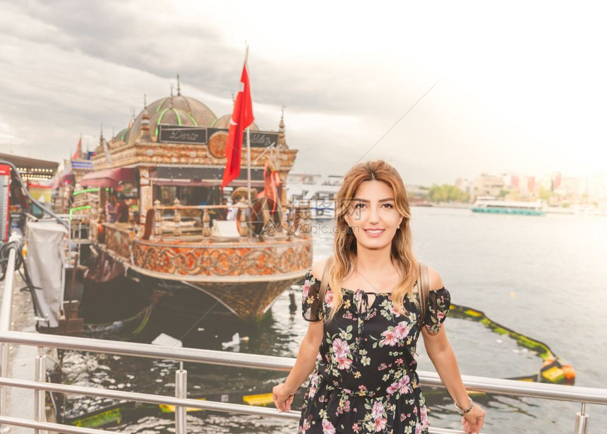 身着裙子的美女站在船前土耳其伊斯坦布尔出售烧烤鱼图片