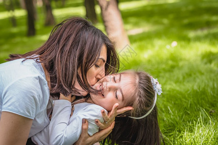 年轻妈拥抱并亲吻她的女儿表示爱与支持关的年轻母亲拥抱女孩图片
