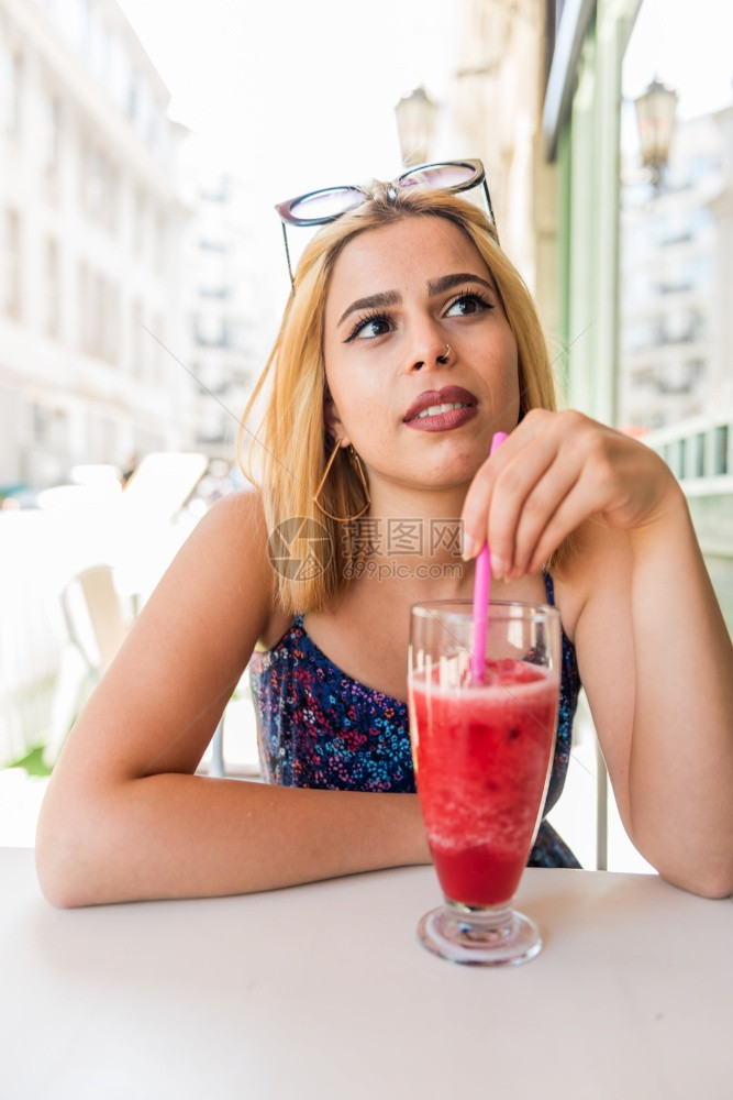 美丽的年轻女子坐在街头咖啡厅和享受生活时喝着水果冰淇淋享受着生活图片