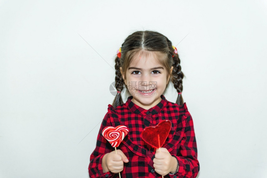 可爱的小女孩在心形红糖中拿着棒图片