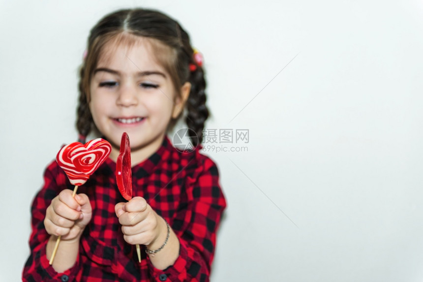 可爱的小女孩在心形红糖中拿着棒图片