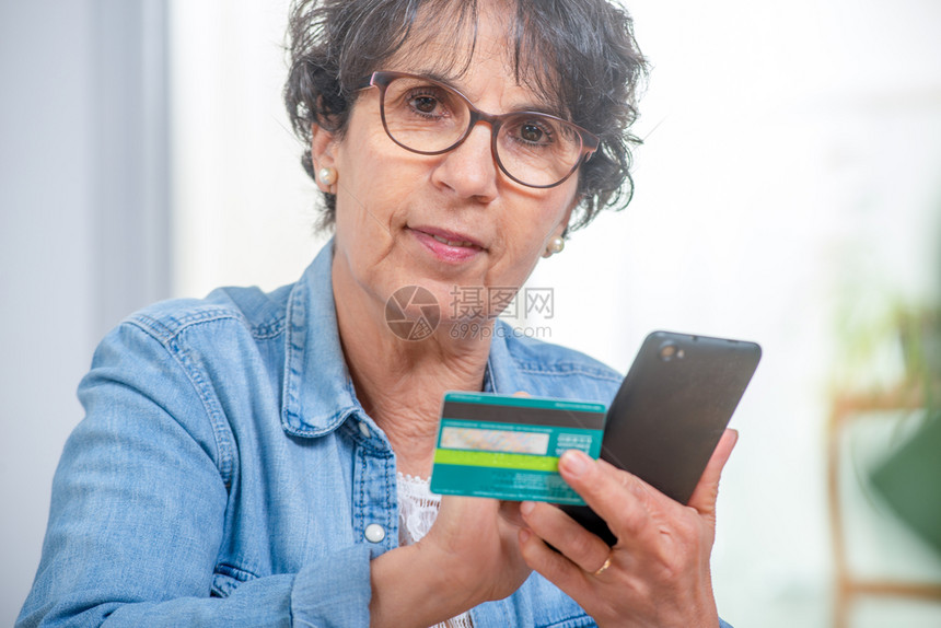 高级黑头发妇女用智能手机和互联网购物图片