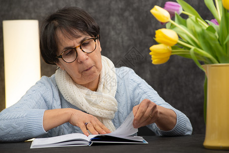 戴眼镜阅读书的黑褐色高龄妇女背景图片