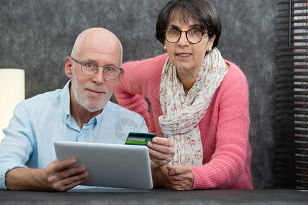 老年情侣在家使用平板电脑背景图片