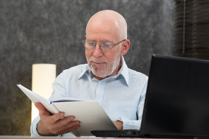有白头发和眼镜的老人阅读一本书图片
