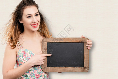笑着的年轻美女展示着一个小黑板背景图片