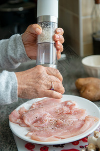 一个女人把盐加在肉上做饭关闭图片