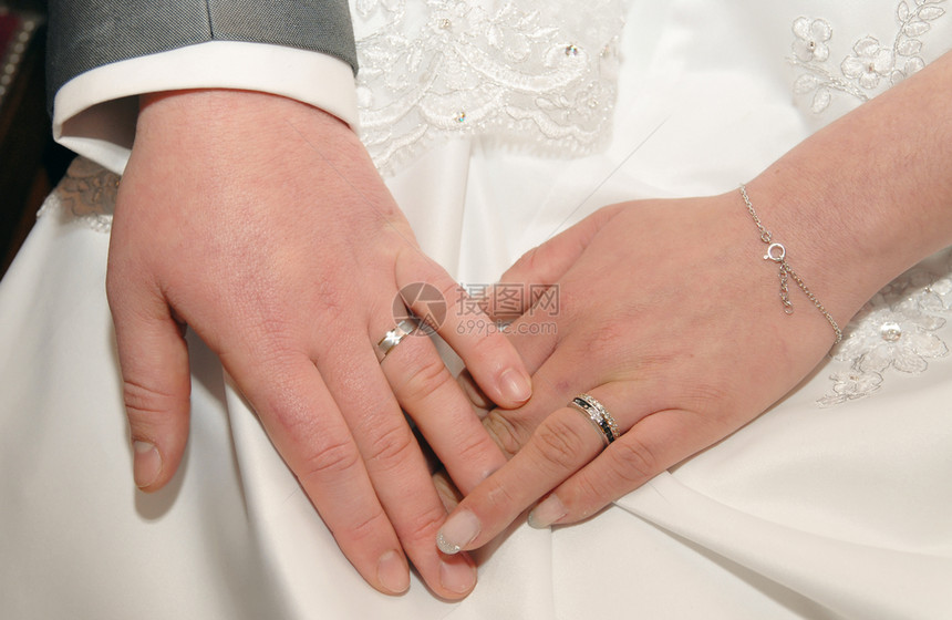 一对夫妇手和戒指在婚礼花束上图片