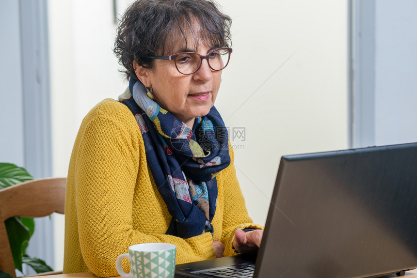一位美丽的黑发女肖像家里有笔记本电脑的成年女子图片